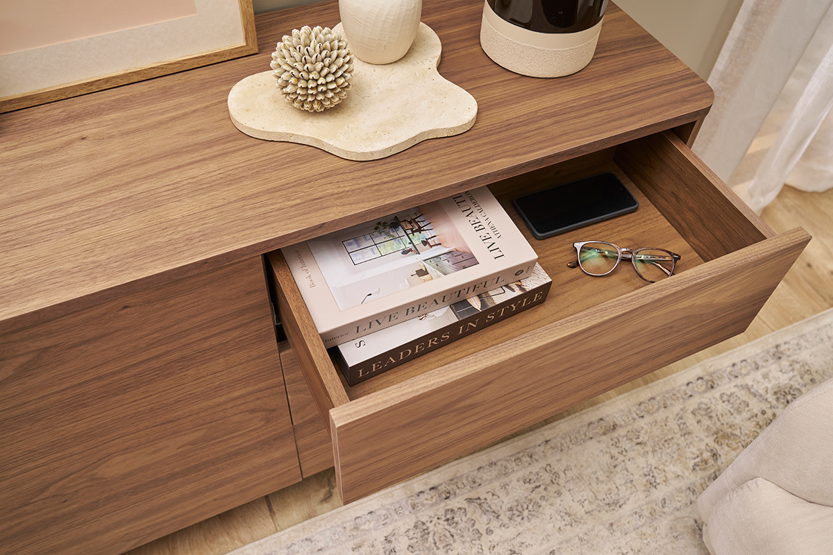 Buffet en bois fonc� avec tiroir ouvert, livres et lunettes rang�s � l'int�rieur.