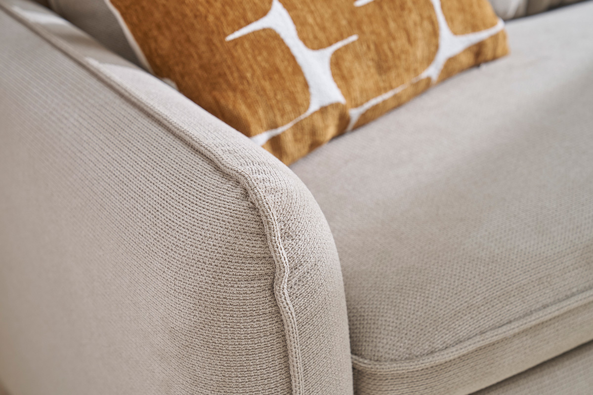 D�tail du canap� d'angle convertible ORSO en tissu chenille beige avec coussin d�coratif.
