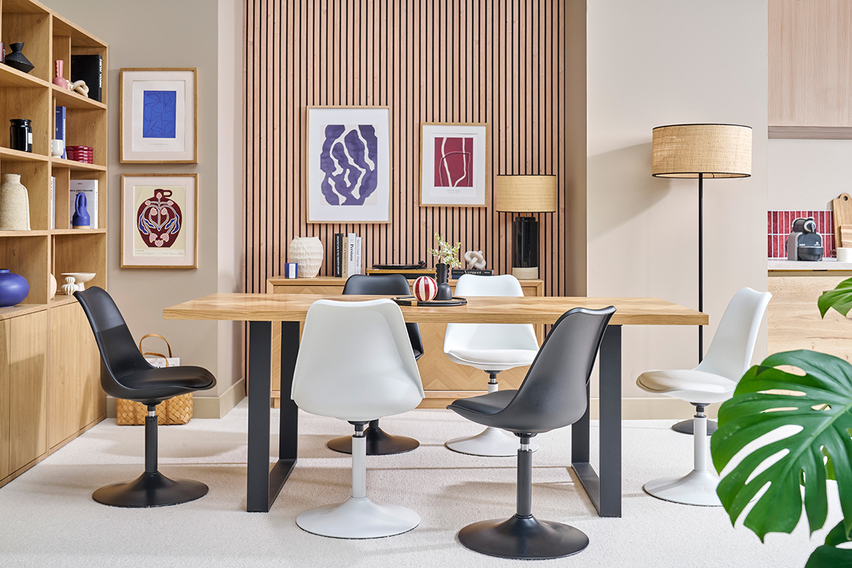 Salle � manger avec chaises pivotantes blanches et noires autour d'une table en bois.