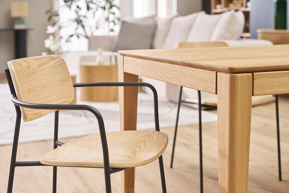 Chaises susan en bois clair avec pi�tement en m�tal noir � c�t� d'une table en bois.