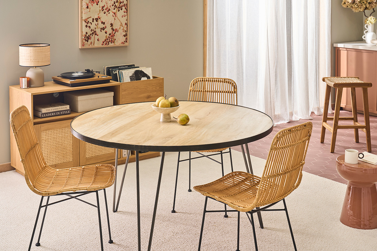 Chaises en rotin et m�tal noir autour d'une table ronde en bois.