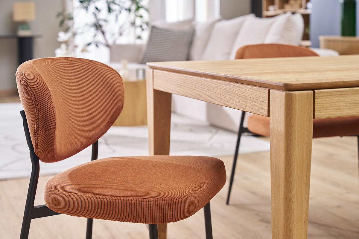 Chaises en velours c�tel� terre br�l�e avec m�tal noir, pr�s d'une table en bois clair.