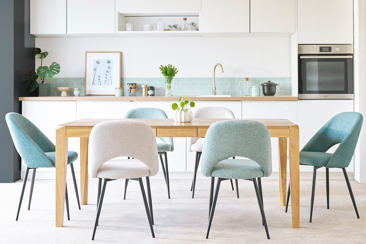 Chaises vert de gris et m�tal noir autour d'une table en bois dans une cuisine moderne.