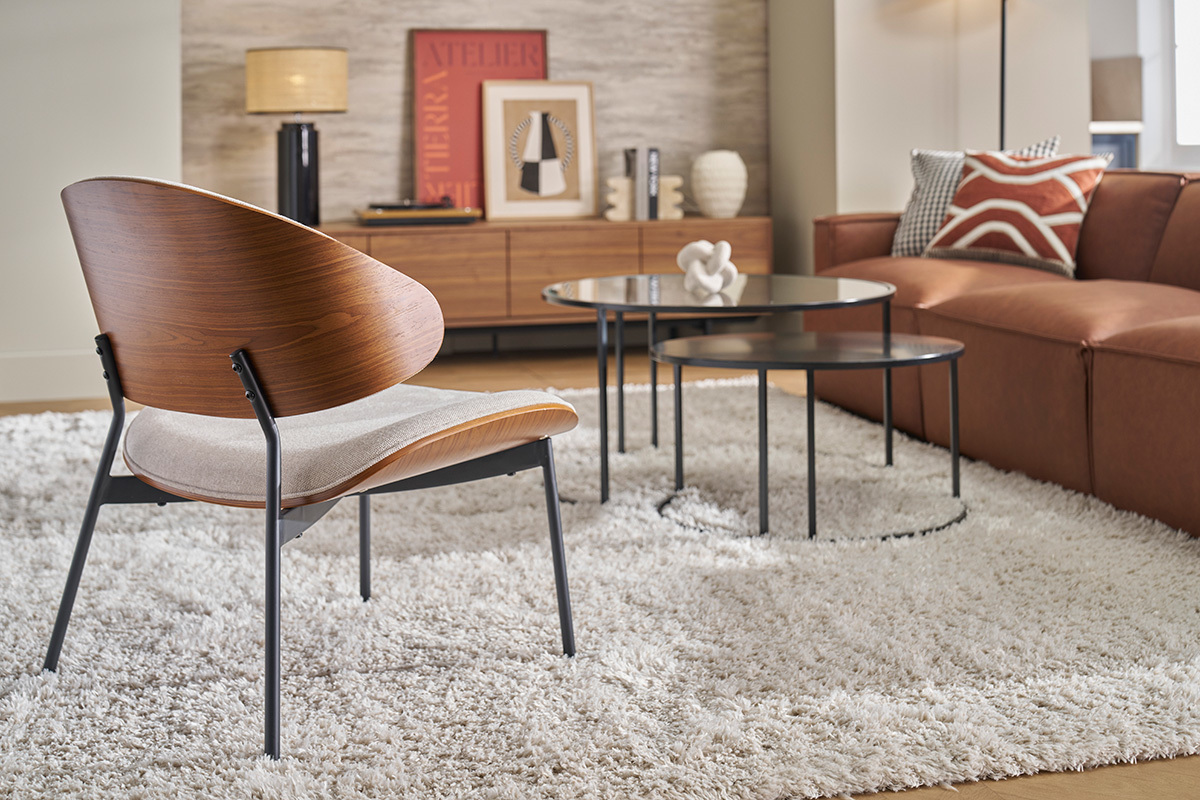 Fauteuil en tissu effet velours beige avec dossier en bois fonc�, pos� sur un tapis, vue arri�re.