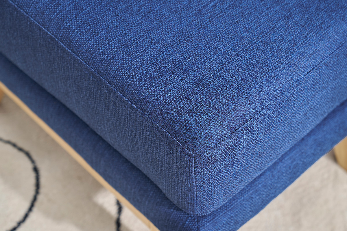 Gros plan sur le tissu bleu fonc� d'un pouf repose-pieds scandinave.