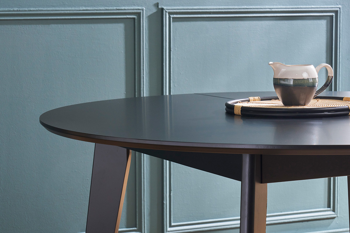 Table � manger ronde noire avec plateau et bord visible, vue partielle.