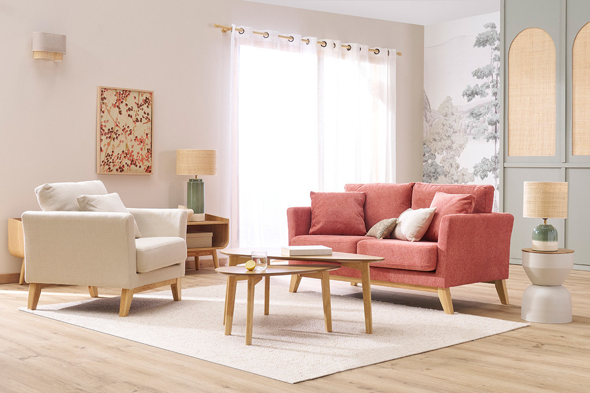 Salon avec table d'appoint ronde en m�tal gr�ge et bois manguier pr�s d'un canap� rose.