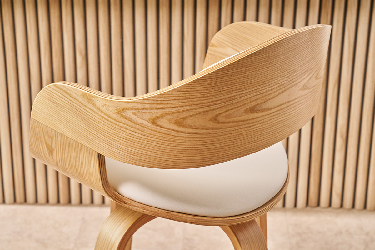 Dossier et assise d'un tabouret de bar scandinave en bois clair et cuir synth�tique blanc, vue de profil.